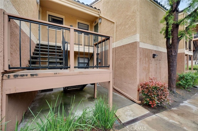 exterior space featuring a balcony, stairs, and stucco siding