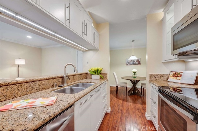 kitchen with white cabinetry, stainless steel appliances, crown molding, and a sink