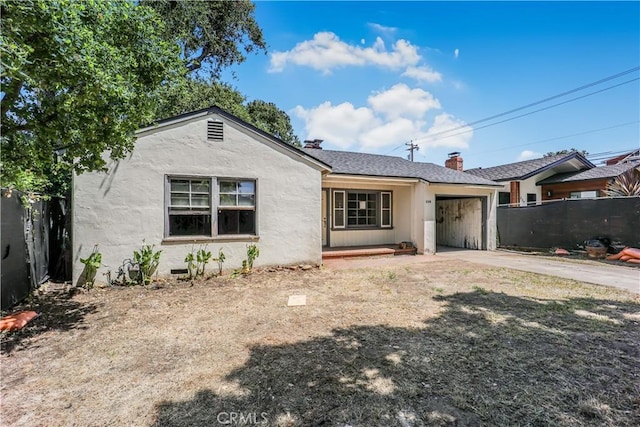 view of front of property featuring an attached garage, stucco siding, fence, a chimney, and driveway