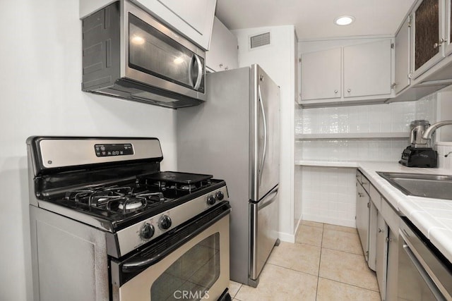 1229 Kilson Dr, Santa Ana, CA 92707 - kitchen with appliances with stainless steel finishes, a sink, tile countertops, light tile patterned flooring, and backsplash