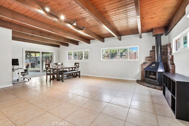 1229 Kilson Dr, Santa Ana, CA 92707 - dining room with light tile patterned flooring, baseboards, a wood stove, and wooden ceiling with exposed beams