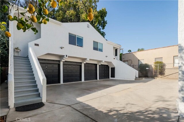 1271 S Sycamore Ave, Los Angeles, CA 90019 - back of property featuring stucco siding, driveway, fence, and stairs