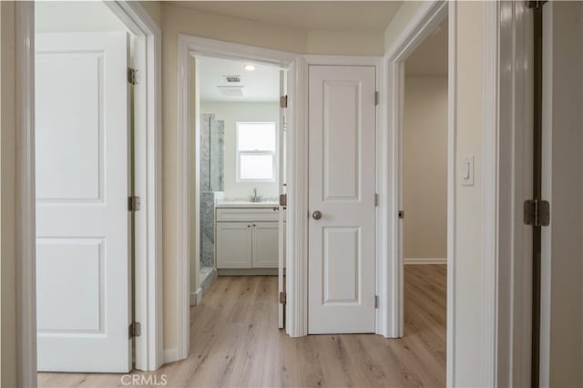 1271 S Sycamore Ave, Los Angeles, CA 90019 - hallway with light wood finished floors, visible vents, baseboards, and a sink
