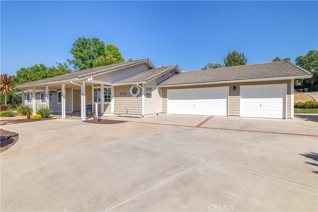 view of front facade with concrete driveway, a garage, a tile roof, stucco siding, and covered porch