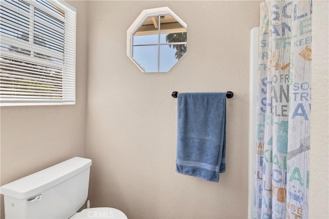 bathroom featuring toilet and curtained shower