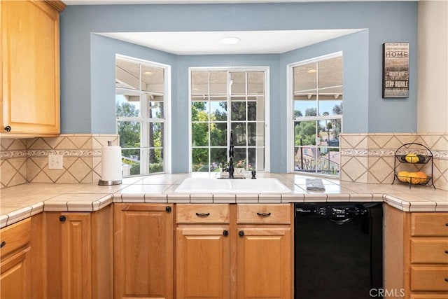 kitchen featuring black dishwasher, a sink, tasteful backsplash, and plenty of natural light