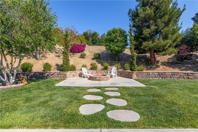 view of grassy yard with an outdoor fire pit and a patio