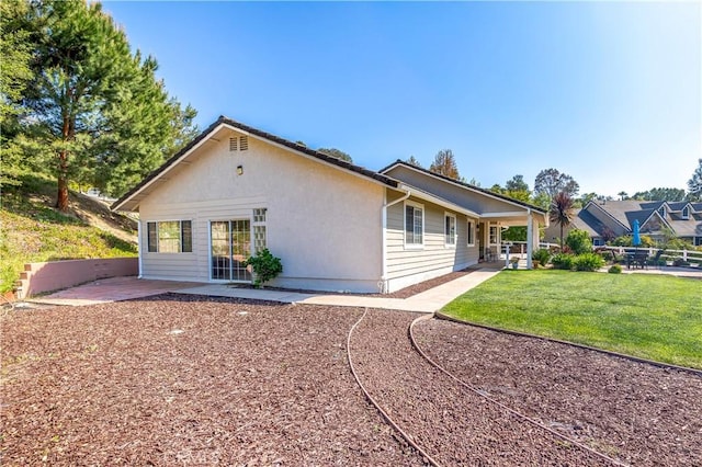 back of property with a lawn and a patio