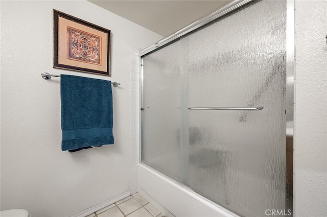 bathroom featuring tile patterned flooring and combined bath / shower with glass door