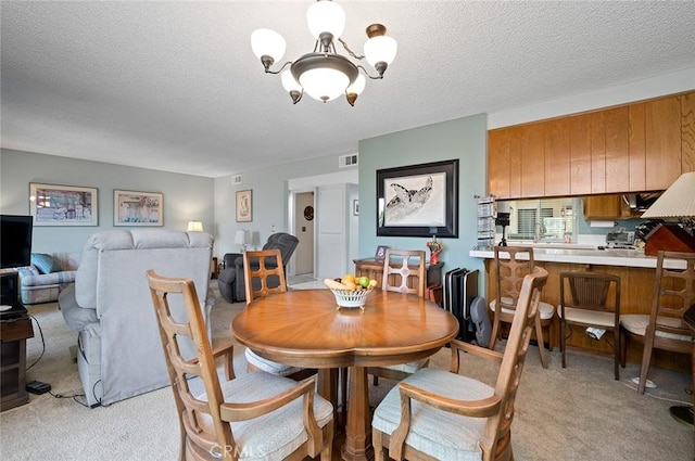 dining room featuring light colored carpet, a textured ceiling, and a notable chandelier
