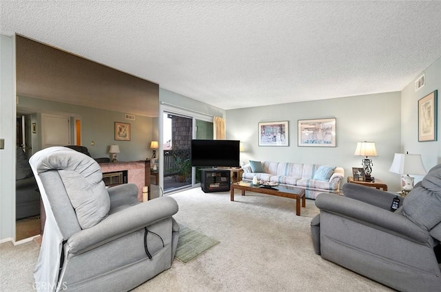living area with carpet flooring, a glass covered fireplace, visible vents, and a textured ceiling