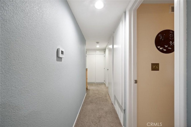hall with light colored carpet and baseboards