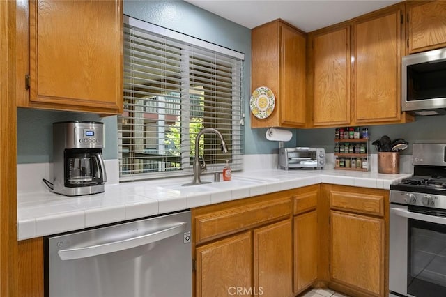 kitchen featuring a sink, brown cabinetry, stainless steel appliances, a toaster, and light countertops