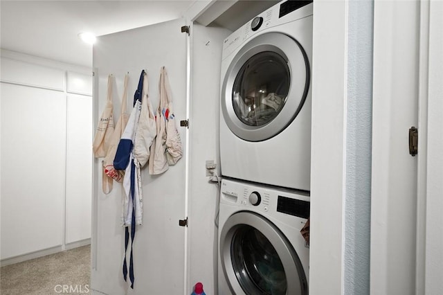 clothes washing area featuring laundry area, carpet floors, and stacked washer and dryer