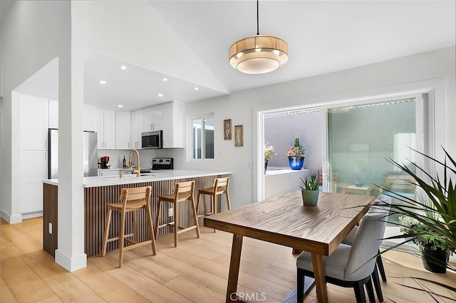 dining area with lofted ceiling, light wood-style flooring, and recessed lighting