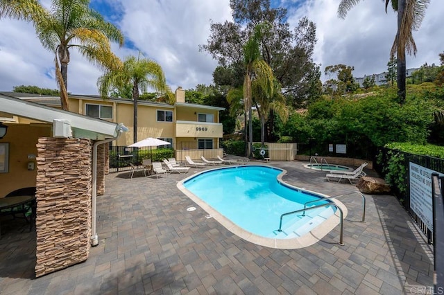 pool featuring fence, a patio, and a community hot tub