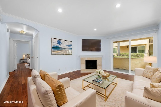 living room featuring arched walkways, baseboards, crown molding, and wood finished floors
