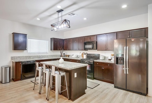 26841 Franklin Ave, Winchester, CA 92596 - kitchen with black appliances, visible vents, hanging light fixtures, dark brown cabinets, and light wood-style floors