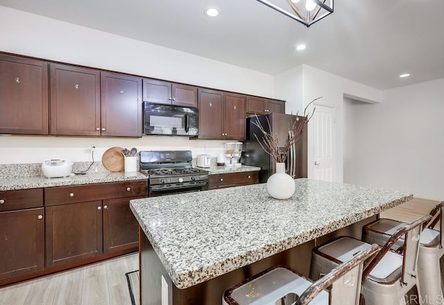 26841 Franklin Ave, Winchester, CA 92596 - kitchen featuring freestanding refrigerator, black microwave, a kitchen bar, gas range, and a kitchen island