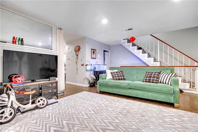 living area with baseboards, stairs, visible vents, and wood finished floors