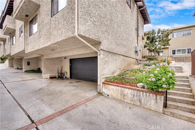 view of side of home featuring concrete driveway, stucco siding, and a garage