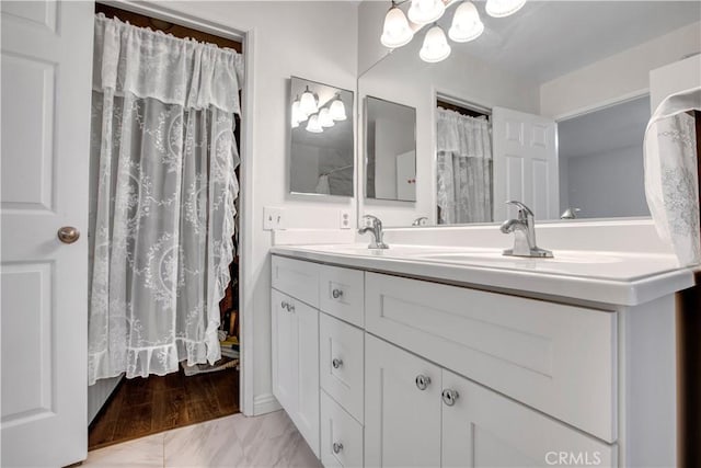 full bathroom with double vanity, an inviting chandelier, marble finish floor, and a sink