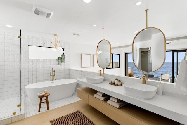 bathroom featuring a sink, a soaking tub, tile walls, and visible vents