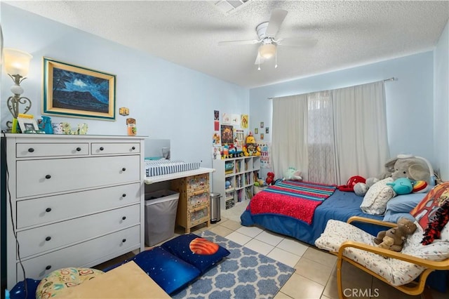 bedroom with light tile patterned floors, visible vents, a ceiling fan, and a textured ceiling
