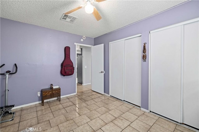 unfurnished bedroom with a textured ceiling, visible vents, two closets, a ceiling fan, and baseboards