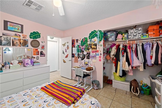 bedroom featuring light tile patterned floors, a closet, visible vents, and a textured ceiling