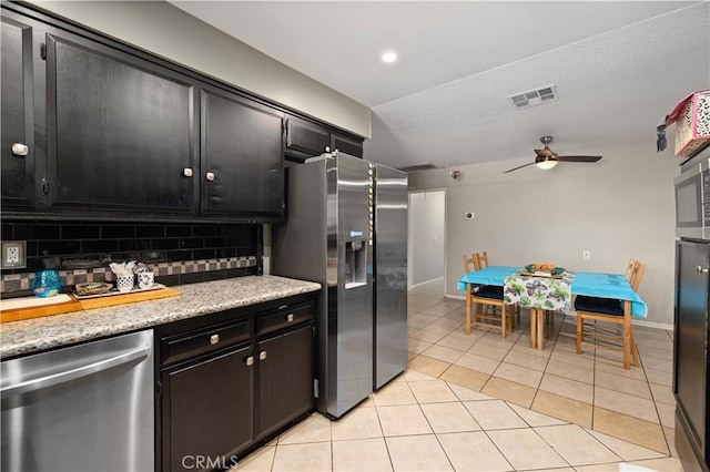 kitchen featuring a ceiling fan, stainless steel appliances, visible vents, decorative backsplash, and dark cabinetry