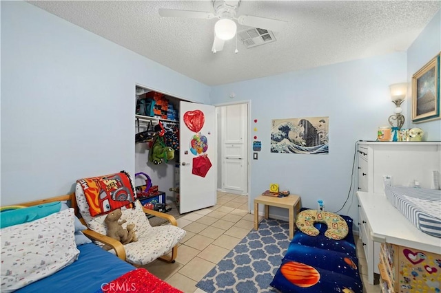 bedroom featuring ceiling fan, a textured ceiling, visible vents, and tile patterned floors