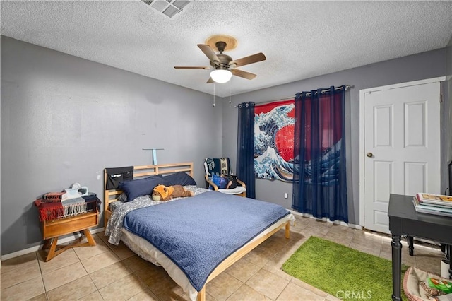 bedroom with light tile patterned flooring, a textured ceiling, visible vents, a ceiling fan, and baseboards
