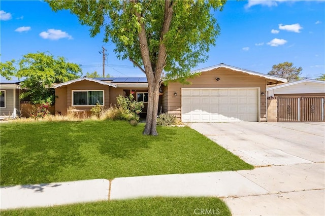 ranch-style home with an attached garage, driveway, solar panels, and a front lawn