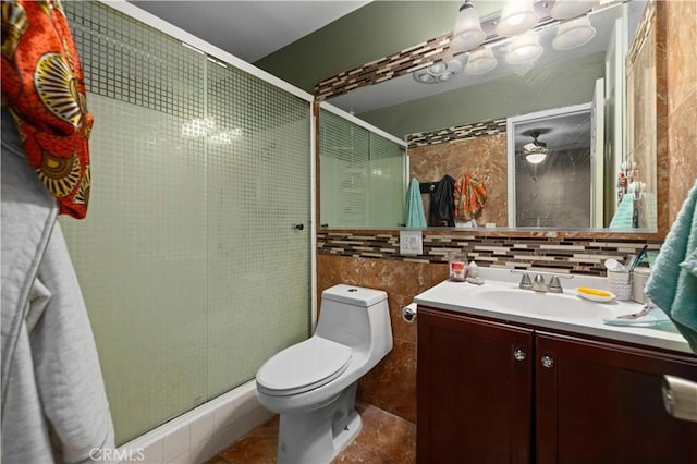 full bathroom featuring tile walls, tasteful backsplash, toilet, vanity, and a stall shower