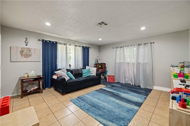 living room with a textured ceiling, light tile patterned floors, visible vents, and recessed lighting