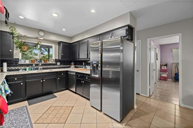 kitchen with dark cabinets, stainless steel appliances, tasteful backsplash, and a sink