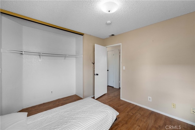 1009 Fairwind Ave, Rosamond, CA 93560 - bedroom featuring a closet, a textured ceiling, baseboards, visible vents, and wood finished floors