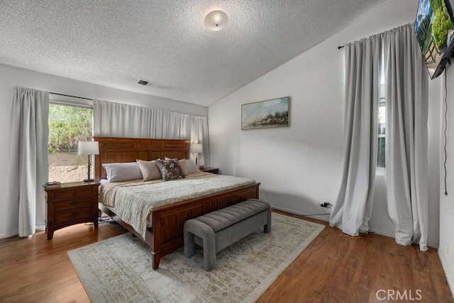 1009 Fairwind Ave, Rosamond, CA 93560 - bedroom with vaulted ceiling, a textured ceiling, visible vents, and wood finished floors