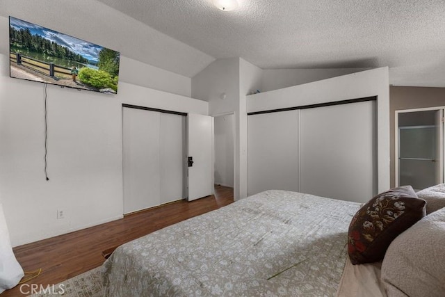 1009 Fairwind Ave, Rosamond, CA 93560 - bedroom with a textured ceiling, wood finished floors, lofted ceiling, and multiple closets