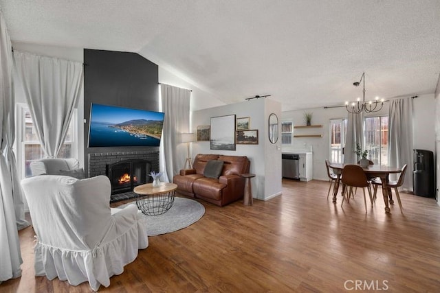 1009 Fairwind Ave, Rosamond, CA 93560 - living area featuring wood finished floors, a textured ceiling, vaulted ceiling, a chandelier, and a brick fireplace