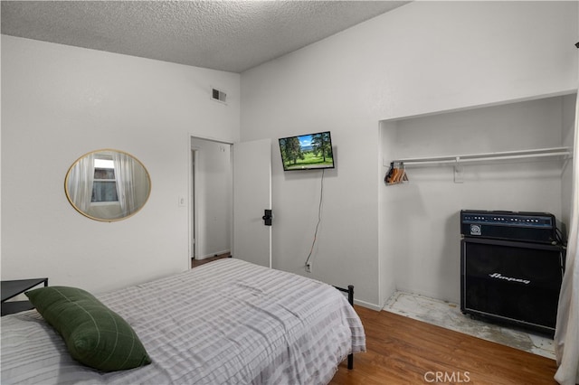 1009 Fairwind Ave, Rosamond, CA 93560 - bedroom with a closet, a textured ceiling, visible vents, vaulted ceiling, and wood finished floors