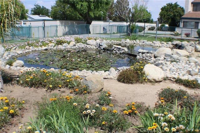 view of yard featuring a garden pond and fence