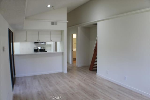 kitchen with lofted ceiling, light wood-type flooring, visible vents, and range