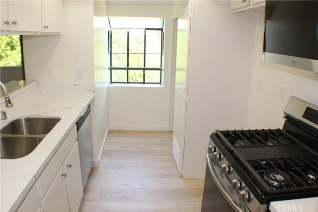 kitchen with a sink, stainless steel appliances, white cabinets, and light wood-style floors