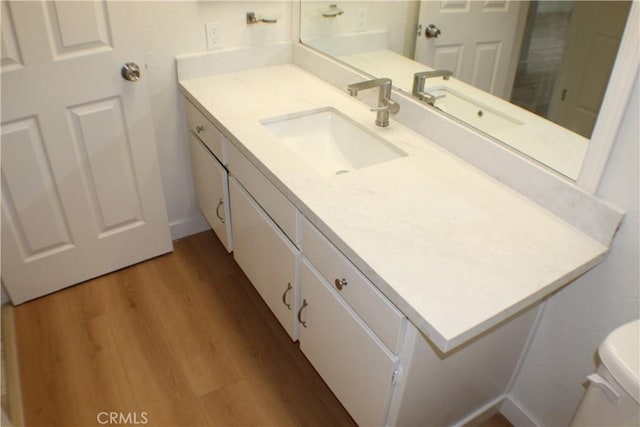 bathroom featuring toilet, baseboards, vanity, and wood finished floors