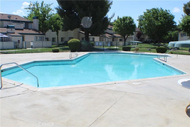 pool with a patio area, a residential view, and fence