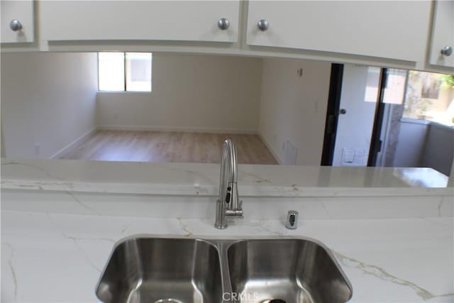 room details with a sink, baseboards, light stone counters, and wood finished floors