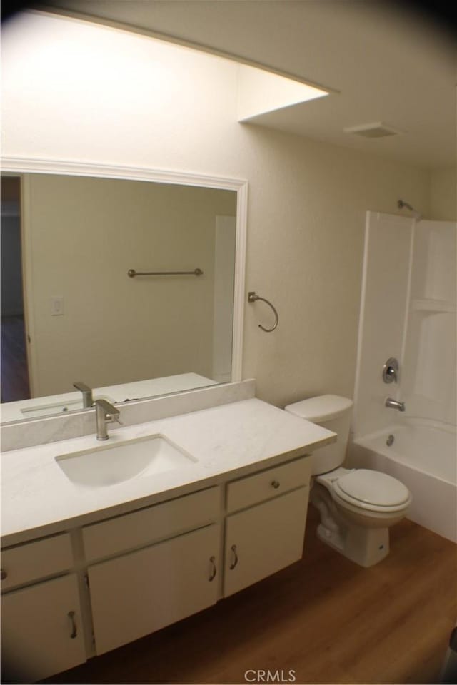 bathroom featuring vanity, tub / shower combination, toilet, and wood finished floors