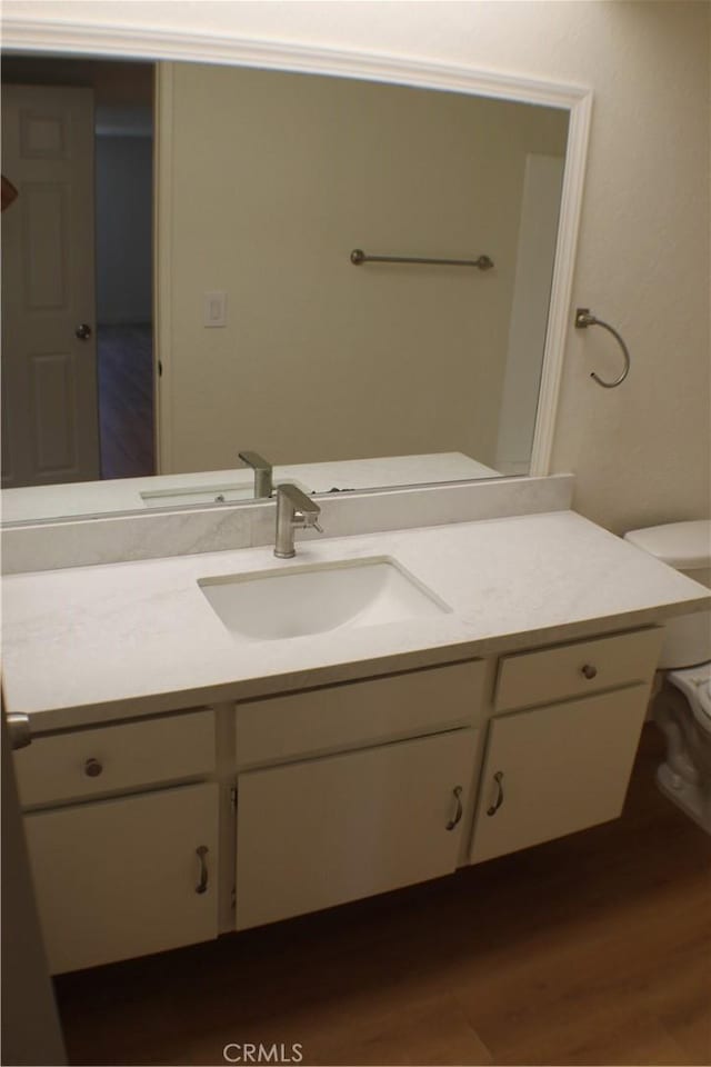 bathroom featuring toilet, wood finished floors, and vanity